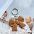 Brown acrylic bow keychain with white pearl and silver metal clasp for keys or bags. - Brown
