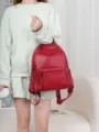 Detailed view of women's red leather backpack, showing durable texture and front zipper. - Burgundy