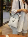 Witte emmertas voor vrouwen, stijlvolle kunstlederen schoudertas met brede riem en slot. - Wit