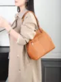 Detailed view of the brown leather shoulder bag worn by a model, showing texture and zipper. - Small Size / Golden Brown