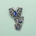 Dettaglio spilla a tripla farfalla in lega color argento vintage con strass blu scuro. - Modello E