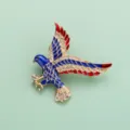 Gros plan broche aigle avec émail bleu rouge, bordure dorée et strass scintillants. - Style R