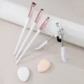 Professional makeup tool set including eyeliner brushes, eyelash curler, and soft puffs. - White