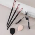 Professional makeup brush set including eyelash curler and soft cosmetic sponge puffs. - Black