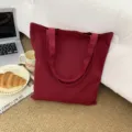 Nahaufnahme einer bordeauxroten Segeltuchtasche in einer gemütlichen Lifestyle-Szene. - Dunkelrot