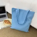 Detailansicht einer blauen Canvas-Tragetasche auf Teppich, zeigt stabile Griffe und Stoff. - Himmelblau