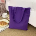 Detailansicht einer minimalistischen lila Kanvastasche in einem gemütlichen Lifestyle-Ambiente. - Traubenlila