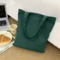 Detailansicht einer dunklen grünen Stofftasche aus Canvas in gemütlicher Zimmerkulisse. - Dunkelgrün