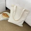 Detailansicht der minimalistischen, beige-farbenen Kanvas-Tragetasche mit stabilen Griffen. - Beige