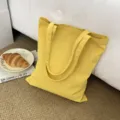 Detailaufnahme einer gelben Segeltuch-Tragetasche auf Teppich mit Frühstücks-Requisiten. - Gelb