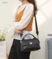 Nahaufnahme einer schwarzen Damen Handtasche aus echtem Leder mit Griff und Gurt. - Schwarz
