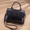 Black leather women top handle shoulder bag with chic crocodile embossed flap design. - Black