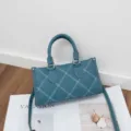 Close-up view of a stylish teal leather shoulder bag with contrast white stitching details. - 24*9*13cm / Blue