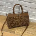 Close-up detail of stylish brown leather and leopard print handbag with metal turn-lock. - Leopard Print