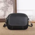Detailansicht der klassischen schwarzen Ledertasche mit feinen weißen Nähten und Beschlägen. - Klein Größe / Schwarz