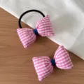 Gros plan sur les détails de l'élastique à cheveux nœud rose et blanc en tissu doux. - Set Chouchou + Barrette Rose