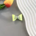 Gros plan détaillé d'une pince à cheveux nœud jaune néon faite main avec des reflets holographiques. - Style de Barrette / Jaune
