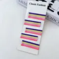 Gros plan de pinces à cheveux colorées en violet, jaune et rose sur une carte de présentation. - Style 3