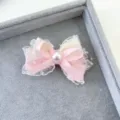 Detail shot of a sweet handmade fabric double layer bow hair clip with pearl and lace trim. - Pink