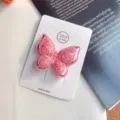 Vue détaillée d'une pince à cheveux papillon double à paillettes roses sur carte. - Pince à Cheveux Rose