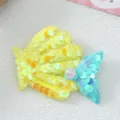 Gros plan détaillé d'une pince à cheveux queue de sirène en sequins colorés avec perle. - Jaune
