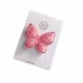 Nahaufnahme Detail einer glitzernden rosa doppelten Schmetterlings-Haarspange auf Karte. - Rosa Material (Ohne Klammer)