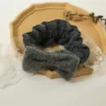 Vista dettagliata della fascia per capelli con fiocco soffice grigio scuro, trucco. - Grigio