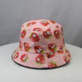 Detailed view of pink cute cartoon strawberry print bucket hat, stylish cotton fabric brim. - One Size / Pink