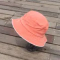 Orange washed distressed bucket hat with white piping, casual sun hat for outdoor wear. - Orange