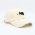 Primer plano de gorra de béisbol en color beige con detalle de bordado de corazón negro. - Talla Estándar (54-59CM) / Blanco Roto