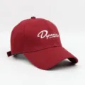 Gedetailleerd overzicht van de bordeauxrode honkbalpet met witte Dynamism-borduursel en klep. - Rood