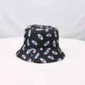 Detalle del sombrero de pescador negro estampado con patrón de ojos azules y textura. - Negro