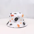 Detail view of the Halloween spider and pumpkin print fabric pattern on the white bucket hat. - White