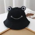 Cute black cotton bucket hat with frog eyes and white embroidered smile for outdoor travel. - Adjustable / Black