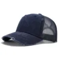 Primer plano de gorra trucker de mezclilla desgastada, azul oscuro con malla trasera transpirable. - Azul marino