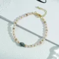 Primer plano detallado de la elegante pulsera de cuentas rosadas con detalles dorados y cadena. - Pulsera Cuentas Rosas y Cuenta Central Gris