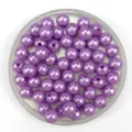Close-up of purple imitation pearl craft beads in a tray, perfect for DIY jewelry making. - Purple
