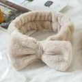 Detail shot of a soft fluffy bow headband in beige, perfect for skincare and makeup routines. - Khaki