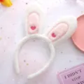 Closeup detail of cute plush bunny ear headband with sweet pink embroidered hearts. - White
