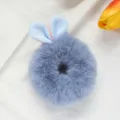Detail view of a fluffy blue plush rabbit ear hair scrunchie, soft hair tie for cute styling. - Blue