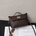 Detailed view of brown leather handbag with metal turn lock closure and shoulder strap. - 22*10*14CM / Coffee