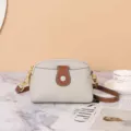 Detail view of the elegant grey leather crossbody bag with brown details and gold chain. - Ivory