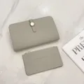 Detailed view of grey leather passport holder and matching card case on a white marble surface. - Off White