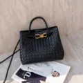 Primo piano dettagliato della borsa a secchiello nera intrecciata con dettagli dorati. - 25 * 9 * 19 cm / Nero