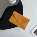 Gros plan détaillé du porte-monnaie en cuir jaune avec texture fine et bouton pression. - Jaune