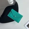 Vue détaillée d'un porte-cartes minimaliste en cuir vert avec bouton-pression et surpiqûres. - Verdoyant