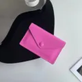 Gros plan détail du porte-monnaie enveloppe en cuir rose, design minimaliste élégant. - Rose rouge