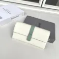 Dettaglio in primo piano di un portafoglio lungo da donna bianco con cinturino verde. - Bianco