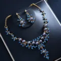 Elegantes goldfarbenes Schmuckset mit blauen Strasssteinen und dunklen Perlen für Damen. - Set mit blauen Strasssteinen und blauen Kunstperlen