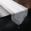 Primer plano detallado de camino de mesa de encaje blanco con elegante bordado de plata y borla. - 40x150cm Puntiagudo / Plata